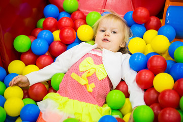 Fototapeta na wymiar THE BABY IS PLAYING IN COLORED BALLS