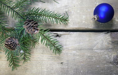Christmas and New Year Concept. Fir tree branch with cones and blue New Year ball on wooden board, Top view, flat lay..