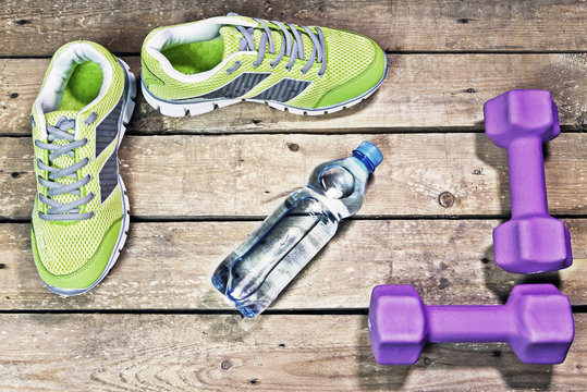 Sports sneakers, dumbbells, drinking water on a wooden background, hdr,  flat lay