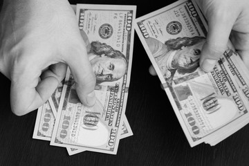 The white young man counts the money, one hundred new dollar bills on a black background close...