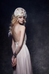 Beautiful blond woman in dress with naked back and a tiara on her head. Fabulous fairy with long blonde hair. Soft skin and beautiful makeup