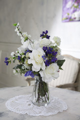 the Bouquet of artificial roses, phlox and bells on a table in a vase, as an interior decoration