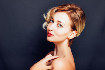 Blonde girl with a short stylish haircut on a dark background

