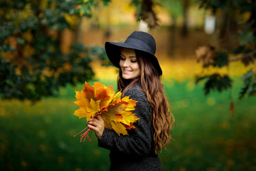 woman with autumn leaves in hand and fall yellow maple garden background