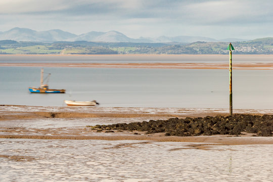 Two boats move as the tide starts to come back in within Morecambe Bay. This long exposure creates an impression of movement in an otherwise still scene.