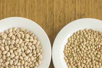 White dishes with raw bean and lentil