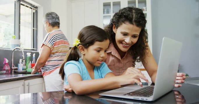 Mother and daughter using laptop in kitchen 