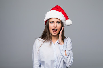 surprised christmas woman wearing a santa hat smiling isolated over gray background