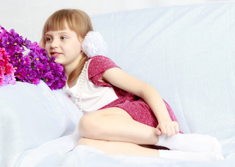 Girl sits next to a bouquet of flowers.