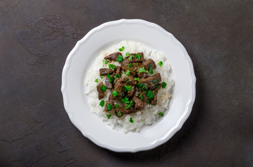 Cooked rice and fried beef with parsley served in white plate on
