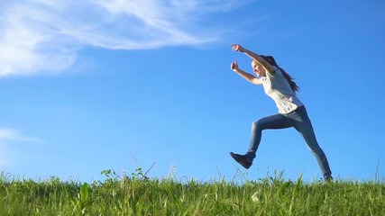 Happy girl running on green grass hill against blue sky