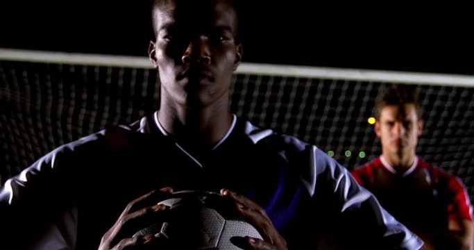 Portrait of confident African American man soccer player holding ball with rival athlete 