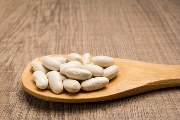 Navy Bean legume. Grains in wooden spoon. Rustic.