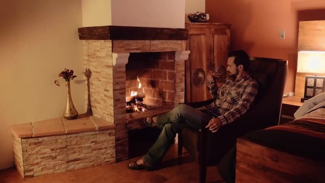Man in front of fireplace drinking a glass of red wine. 4k