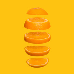 Creative concept with flying orange. Sliced orange on yellow background. Levity fruit floating in the air