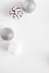 White Christmas background. Frosty pine cones, white colored decoration balls. Minimalist style. Copyspace for text, overhead, vertical