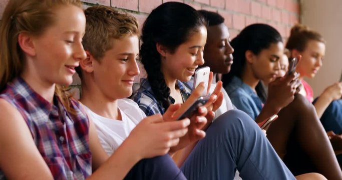 Group of school friends using mobile phone 