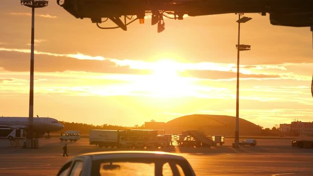 Airplanes and ground support equipment against sunset sky at the airport