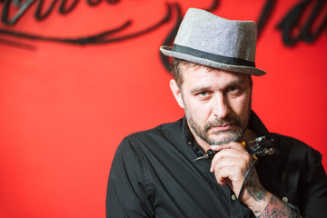 Bearded male tattoo master posing with tattoo machine gun