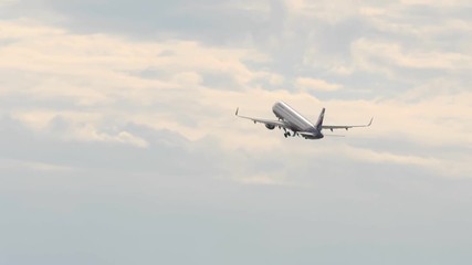 Passanger airplane retracts landing gear after take off and flies away in overcasted sky
