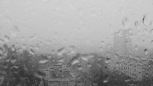 Rain drops on the window and city outside black and white