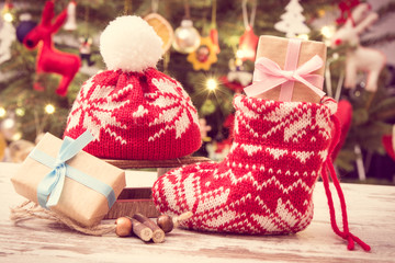 Vintage photo, Gift for Christmas with woolen sock and cap on background of christmas tree with decoration