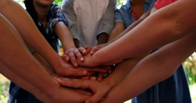 Schoolkids forming hand stack in school premises 