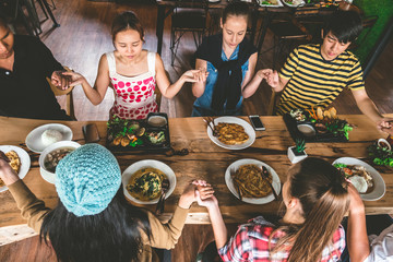 Group of friend pray before having nice food and drinks, enjoying the party and communication, Top view of Family gathering together at home for eating dinner.