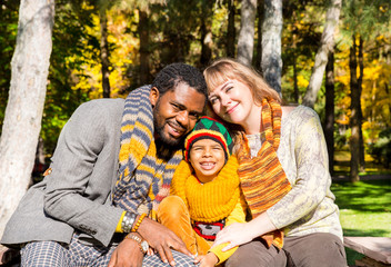 Fototapeta na wymiar Happy family in autumn park. African American family: black father, mom and child boy on nature in fall.
