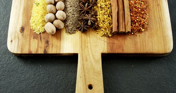Various spices arranged in row on wooden tray 