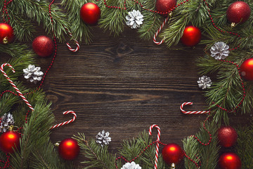 Christmas background with pine branches and red decorations on dark wooden boards. Space for text.