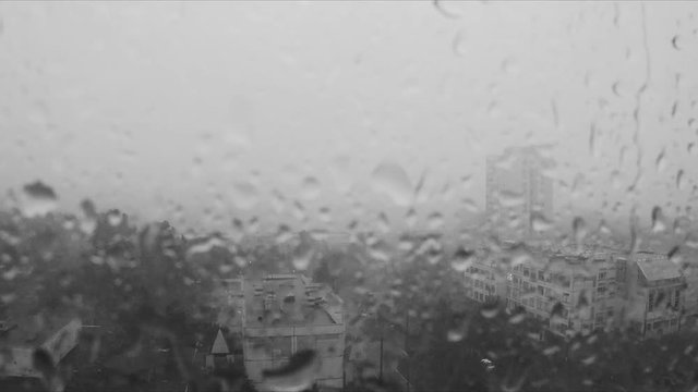 Rain drops on the window and the city outside black and white