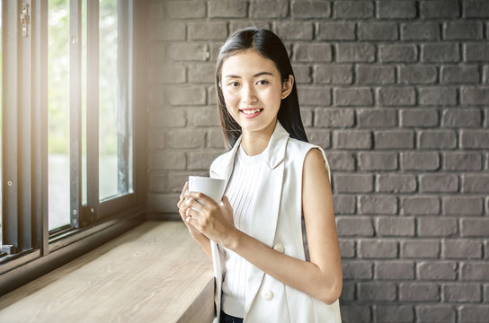 Image of young and pretty asia woman with cup of coffee smile in cafe