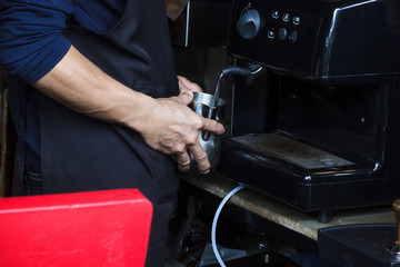 Barista using coffee machine to Steaming milk froth for preparing coffee. Microfoam is milk formed using a steam wand on an espresso machine.