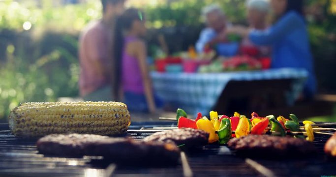Corn, sausages and meat being grilled on barbecue 