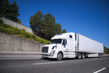 Big rig semi truck with reefer semi trailer going on highway with commercial cargo for delivery