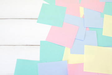 Many pastel color post it note paper sheet stick on white table office with copy space background.