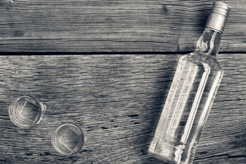 Black and white photo. VODKA luxury. Vodka in a bottle and glasses on a background of wood.