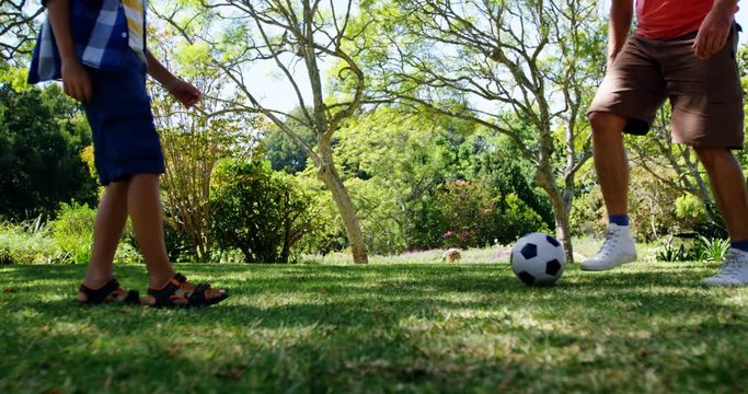 Father and son playing football in park 
