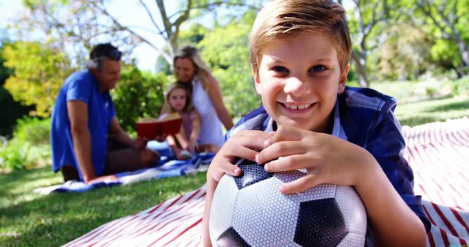 Smiling boy leaning on his football in picnic at park 