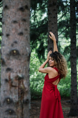 girl in the woods in red dress making pose
