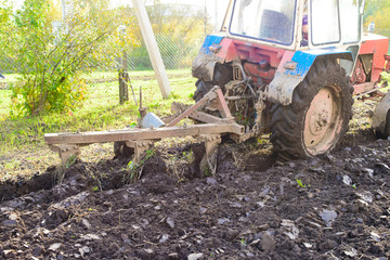 Tractor plowing a land, rural life in Russia. Concept of agriculture, farming, poverty and decline
