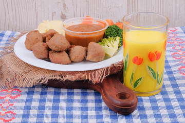 Meatballs with cucumber, carrot, brocolli, black pepper sauce , mashed potato and  corn juice over wooden table. Healthy eating concept.
