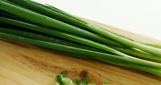 Chopped scallions with knife on chopping board 