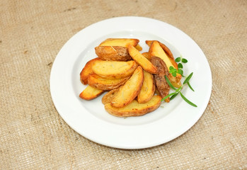 Fried potato wedges with herbs on plate.