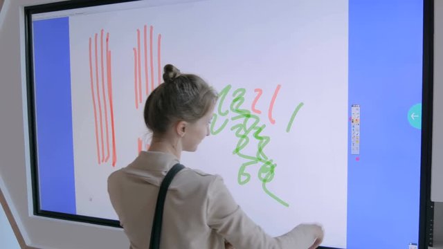 Woman using interactive touchscreen display for drawing at modern technology show. Future and entertainment concept