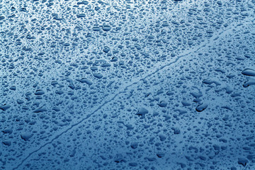 Rain drops on blue color metal car surface.