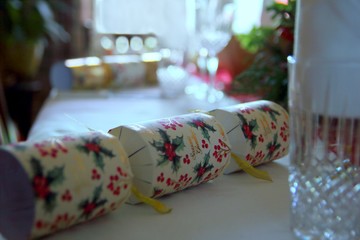 Christmas crackers, glasses, cutlery and serviettes laid out ready for a festive dinner in a traditional home
