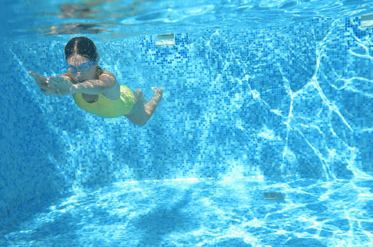 Young girl swimmer swimming under water in pool and has fun, teenager diving underwater, family vacation, sport and fitness concept

