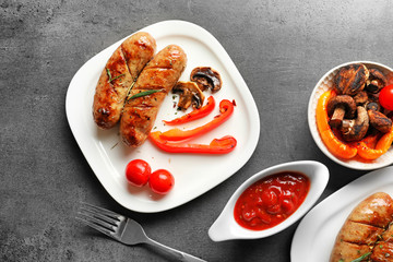 Composition with grilled sausages, vegetables and sauce on grey background